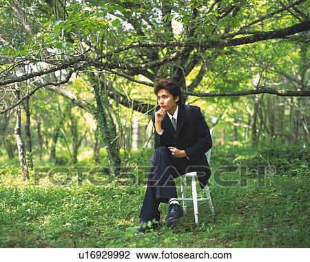 Stock Image - Image of a Businessman Sitting on a Chair in the Forest, Thinking About Something, Side View. Fotosearch