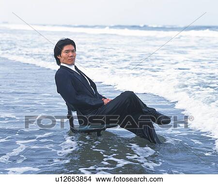 Image of a Businessman Sitting on an Office Chair in the Middle of the Beach, Side View, Looking at Camera View Large Photo Image Picture - Image of a Businessman Sitting on an Office Chair in the Middle of the Beach, Side View, Looking at Camera. Fotosearch