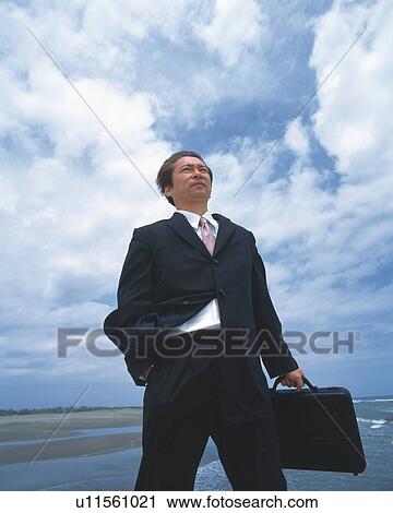 Image of a Businessman Standing By the Sea With a Suitcase Under a Blue Sky, Low Angle View View Large Photo Image Stock Image - Image of a Businessman Standing By the Sea With a Suitcase Under a Blue Sky, Low Angle View. Fotosearch
