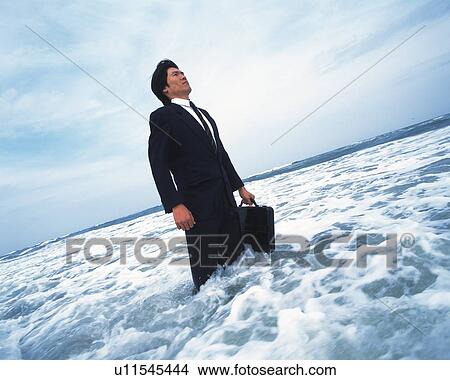 Image of a Businessman Standing in the Ocean With a Suitcase in his Hand, Side View View Large Photo Image Picture - Image of a Businessman Standing in the Ocean With a Suitcase in his Hand, Side View. Fotosearch