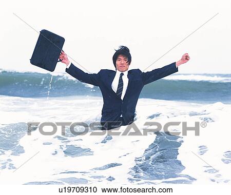 Stock Image - Image of a Businessman Standing in the Ocean Water With a Suitcase in his Hand, Stretching Out His Arms, Front View, Looking at Camera. Fotosearch