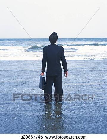 Image of a Businessman Standing in the Sea With his Suitcase in his Hand, Rear View View Large Photo Image Stock Photography - Image of a Businessman Standing in the Sea With his Suitcase in his Hand, Rear View. Fotosearch