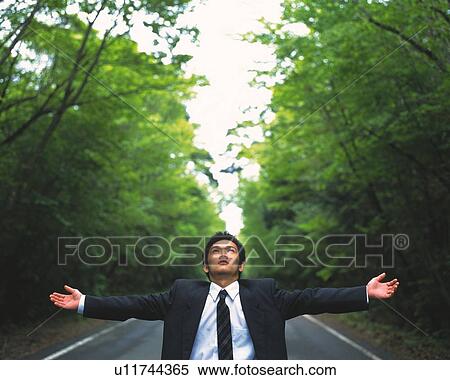 Image of a Businessman With Arms Wide Open Standing on a Street Surrounded By Trees, Looking Up, Front View, Differential Focus View Large Photo Image Stock Photography - Image of a Businessman With Arms Wide Open Standing on a Street Surrounded By Trees, Looking Up, Front View, Differential Focus. Fotosearch