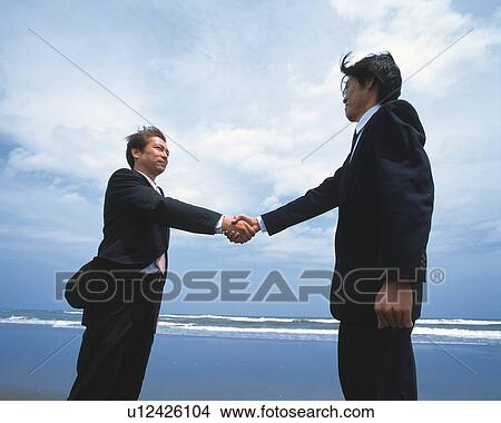 Image of Two Businessmen Shaking Hands at the Beach Under a Blue Sky, Low Angle View, Side View View Large Photo Image Picture - Image of Two Businessmen Shaking Hands at the Beach Under a Blue Sky, Low Angle View, Side View. Fotosearch