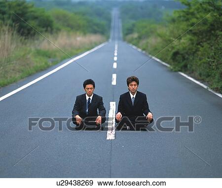 Stock Photo - Image of Two Businessmen Sitting on the Middle of a Road Crossed-legged, High Angle View, Looking at Camera, Differential Focus. Fotosearch