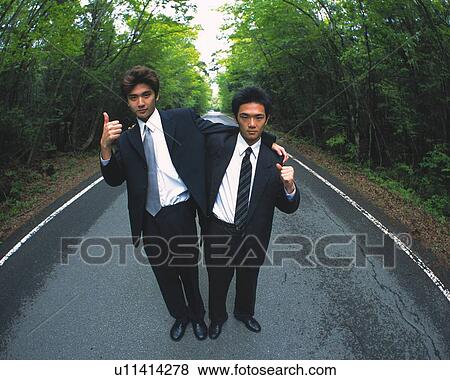 Stock Photo - Image of Two Businessmen Standing in the Middle of a Street Arm in Arm, Both Posing, Looking at Camera, High Angle View. Fotosearch