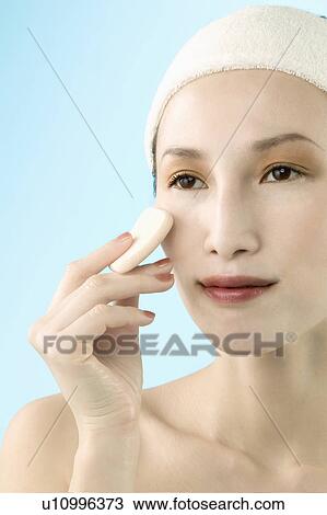 Stock Image - Mid Adult Woman Applying Face Powder. Fotosearch