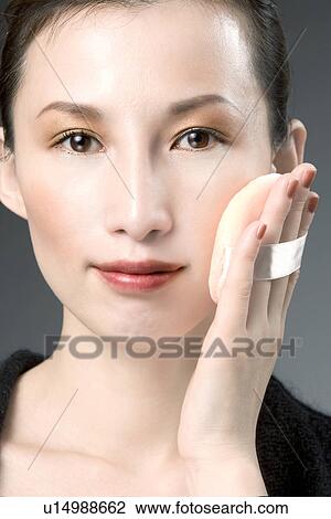 Stock Image - Mid Adult Woman Applying Face Powder. Fotosearch