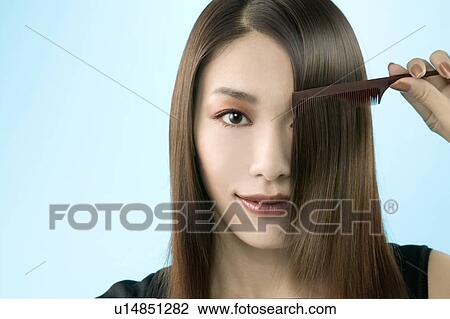 Stock Image - Young Woman Combing Hair. Fotosearch
