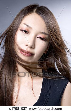 Stock Photo - Young Woman Looking down, Hair Blowing in Face. Fotosearch