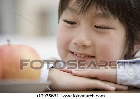 Stock Image - Boy looking at an apple. Fotosearch
