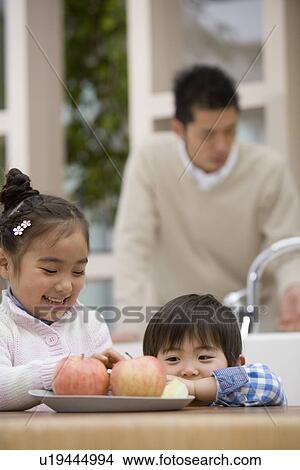 Brother and Sister are looking at an apple View Large Photo Image Picture - Brother and Sister are looking at an apple. Fotosearch