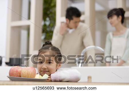 Stock Image - Girl looking at an apple. Fotosearch