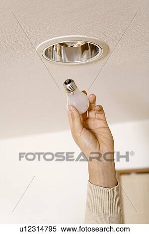 Mid Adult Man reaching to change the light bulb View Large Photo Image Stock Photography - Mid Adult Man reaching to change the light bulb. Fotosearch
