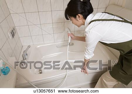 Stock Image - Mid Adult Woman cleaning the bathroom. Fotosearch