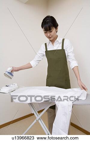 Stock Image - Mid Adult Woman do the ironing. Fotosearch