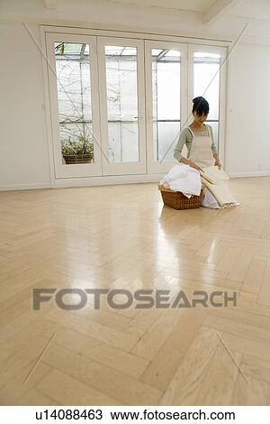 Stock Image - Mid Adult Woman folding the laundry. Fotosearch