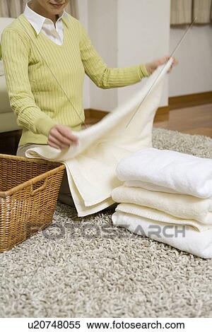 Stock Photography - Mid Adult Woman folding the laundry. Fotosearch