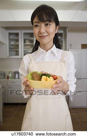 Stock Image - Mid Adult Woman holding a lunch box. Fotosearch