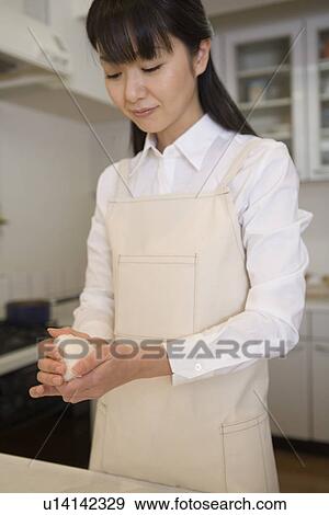 Stock Photo - Mid Adult Woman making a rice ball. Fotosearch