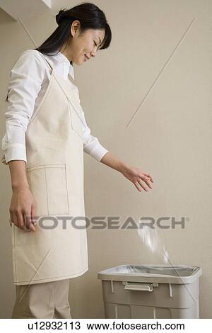 Stock Image - Mid Adult Woman throw a PET bottle for a recycle. Fotosearch