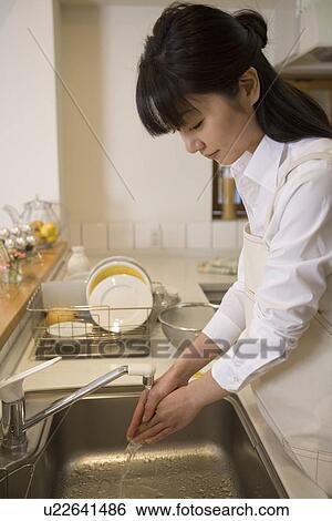 Stock Photograph - Mid Adult Woman washing a hand. Fotosearch