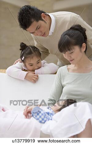 Parents looking at the son sleeping View Large Photo Image Stock Photo - Parents looking at the son sleeping. Fotosearch