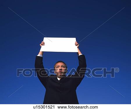 Stock Image - Businessman Holding Up A Card, Low Angle View, Copy Space. Fotosearch