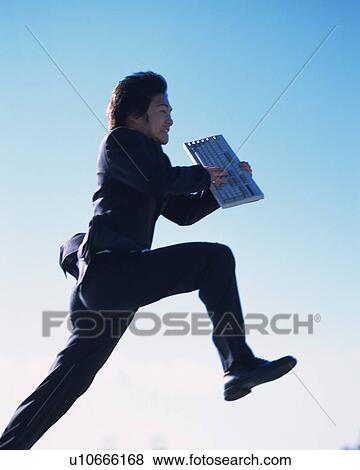 Stock Photo - Businessman Jumping and Holding Keyboard, Side View. Fotosearch
