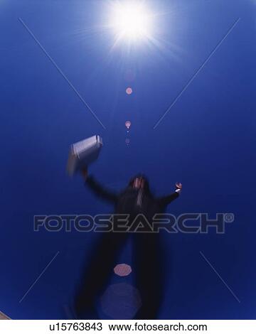 Stock Image - Businessman Jumping, Low Angle View, Lens Flare, Long Exposure. Fotosearch