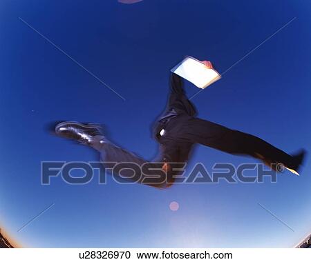 Stock Image - Businessman Jumping, Low Angle View, Lens Flare, Long Exposure. Fotosearch