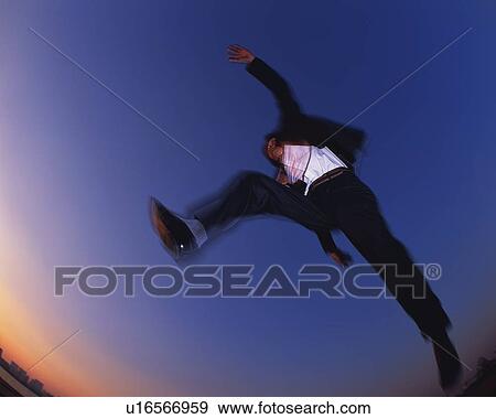 Stock Photo - Businessman Jumping, Low Angle View, Long Exposure, Copy Space. Fotosearch