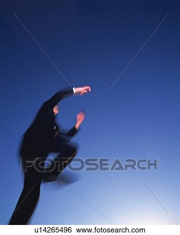 Stock Photograph - Businessman Jumping, Low Angle View, Long Exposure, Copy Space. Fotosearch