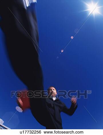 Stock Photograph - Businessman Jumping, Low Angle View, Lens Flare, Long Exposure. Fotosearch