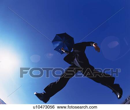 Businessman Jumping with Umbrella, Low Angle View, Lens Flare, Copy Space View Large Photo Image Stock Photograph - Businessman Jumping with Umbrella, Low Angle View, Lens Flare, Copy Space. Fotosearch