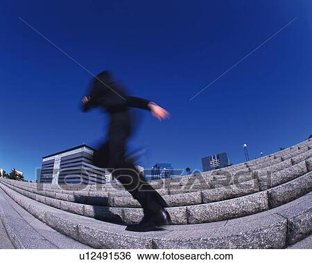 Stock Photograph - Businessman Running Up the Stairs, Rear View, Low Angle View, Long Exposure, Fish Eye. Fotosearch