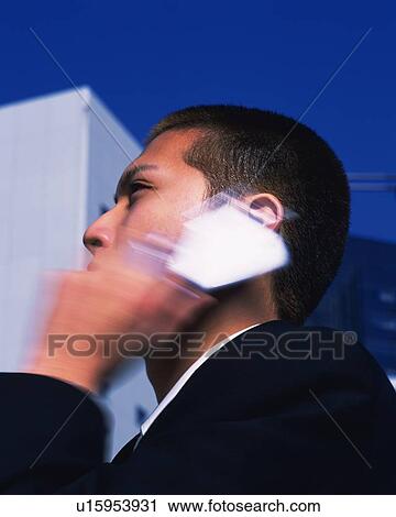 Stock Image - Businessman Talking on Mobile Phone, Side View, Long Exposure, Differential Focus. Fotosearch