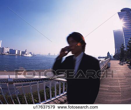 Stock Photo - Businessman Talking on Mobile Phone, Side View, Lens Flare, Long Exposure. Fotosearch