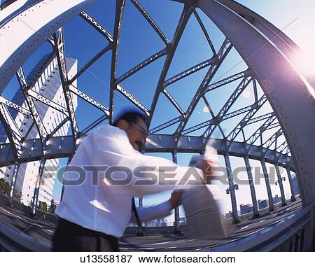 Businessman Walking and Reading Newspaper, Side View, Low Angle View, Lens Flare, Long Exposure, Fish Eye View Large Photo Image Stock Photo - Businessman Walking and Reading Newspaper, Side View, Low Angle View, Lens Flare, Long Exposure, Fish Eye. Fotosearch
