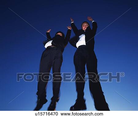 Stock Image - Two Businessmen Jumping, Low Angle View, Long Exposure. Fotosearch