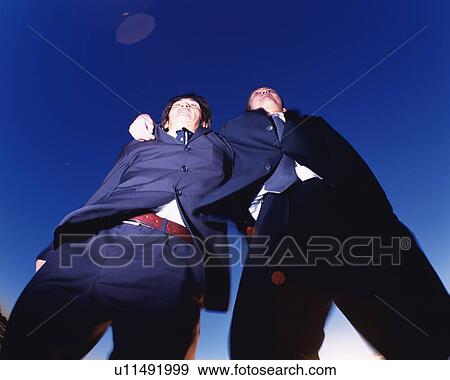 Stock Photo - Two Businessmen Jumping, Low Angle View, Lens Flare. Fotosearch