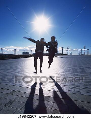 Stock Photo - Two Businessmen Jumping, Low Angle View, Lens Flare, Long Exposure. Fotosearch