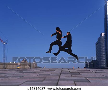 Stock Photo - Two Businessmen Jumping, Side View. Fotosearch