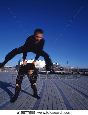 Stock Photography - Two Businessmen Leapfrogging, Front View, Long Exposure. Fotosearch