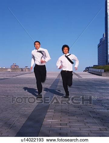 Stock Image - Two Businessmen Running, Front View, Long Exposure, Copy Space. Fotosearch