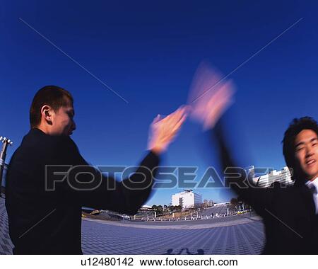 Stock Image - Two Businessmen Slapping Hands, Side View, Front View, Long Exposure, Fish Eye. Fotosearch