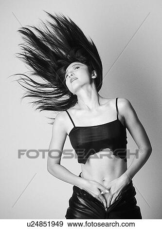 Stock Photo - Portrait of a woman standing in tore top and leather pants, black and white, front view, white background. Fotosearch