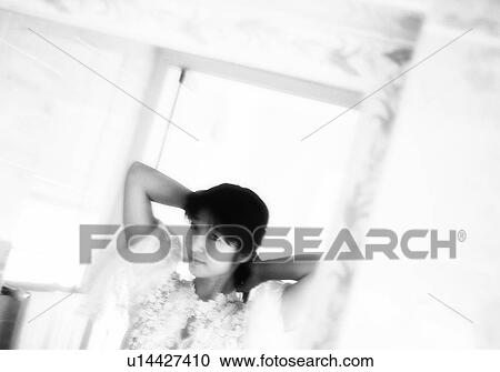Stock Image - Woman in nightie putting her hair up, black and white, front view. Fotosearch