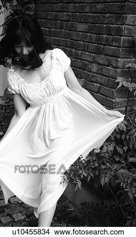 Picture - Woman in white dress walking in garden, black and white, front view. Fotosearch