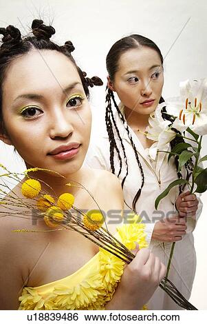 Stock Photograph - Two Young Women Holding Flowers, High Angle View. Fotosearch